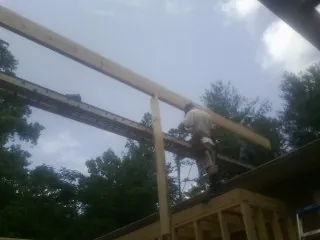 Carpenter setting a ridge beam over a new addition frame — Ice Dam Removal by Roofing Brothers in Thomas