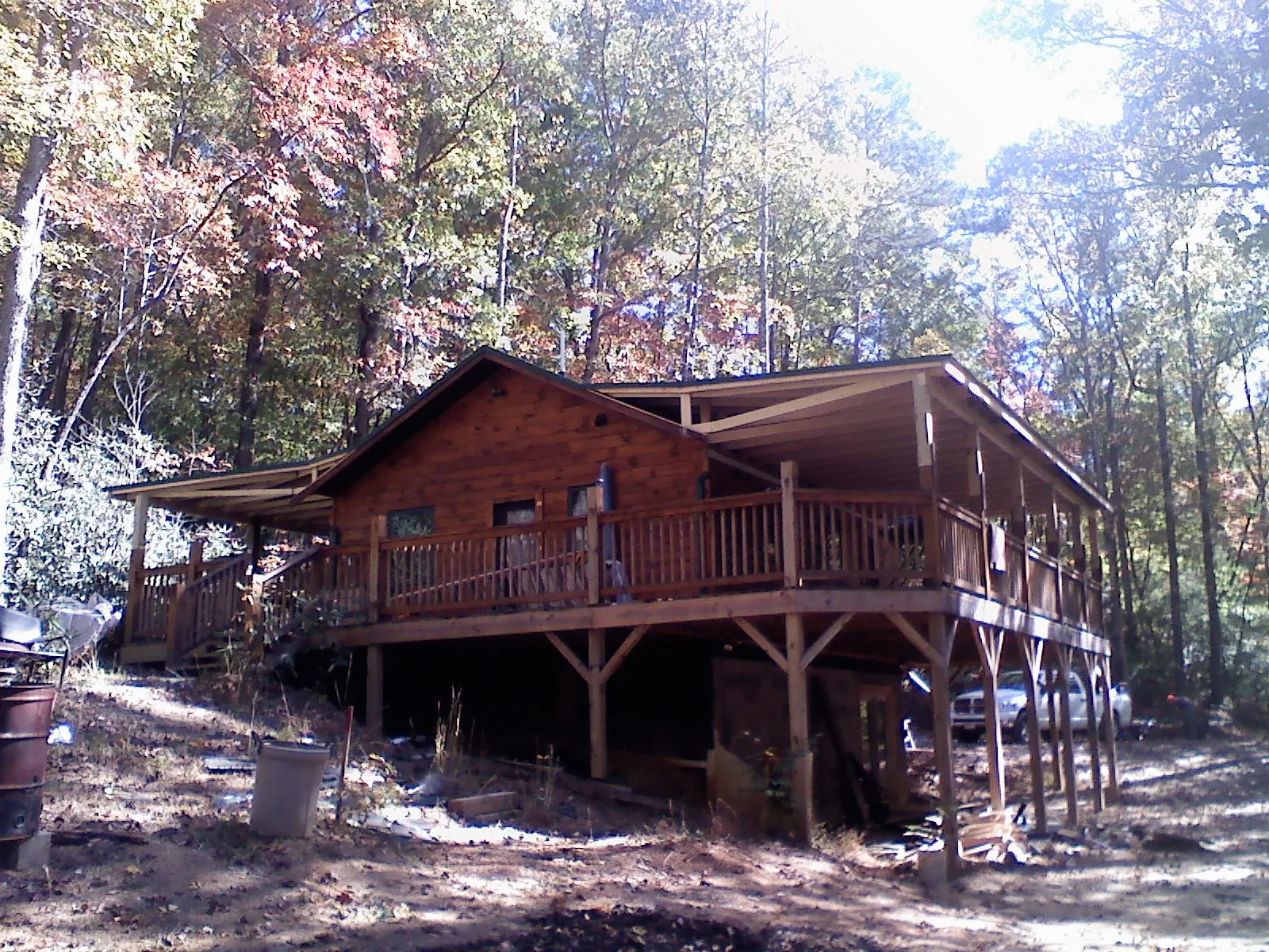 Log cabin with a wraparound porch and metal roof in the fall in Thomas