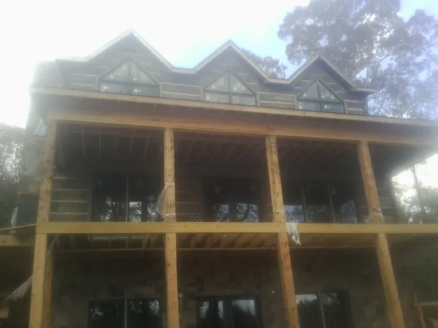 Dormers and porch framing on a large log home under construction — Roof Coating work by our crew in Thomas