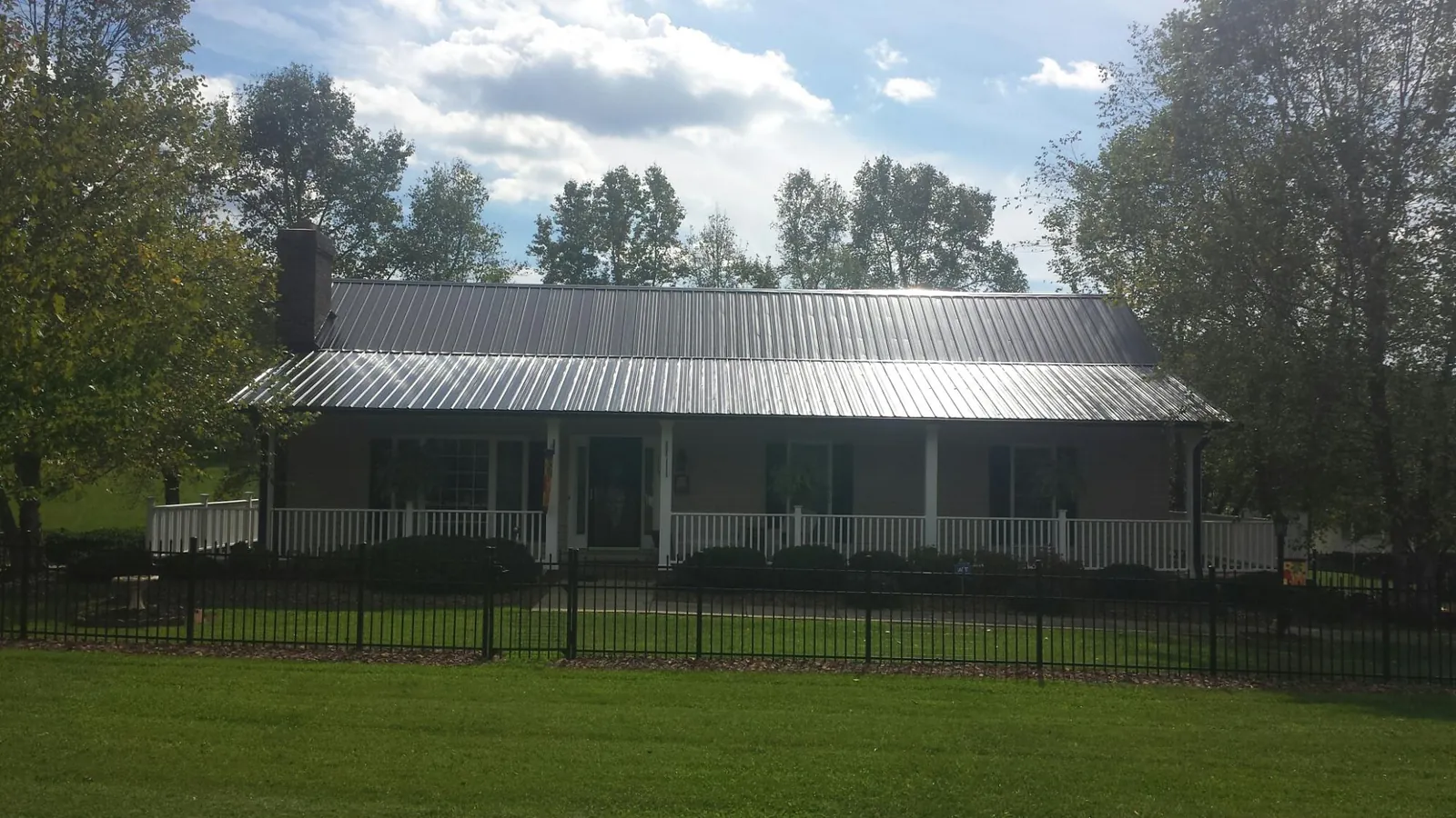 Gray metal roof on a brick ranch with a full width front porch — Gutter Guard Installation work by our crew in Thomas
