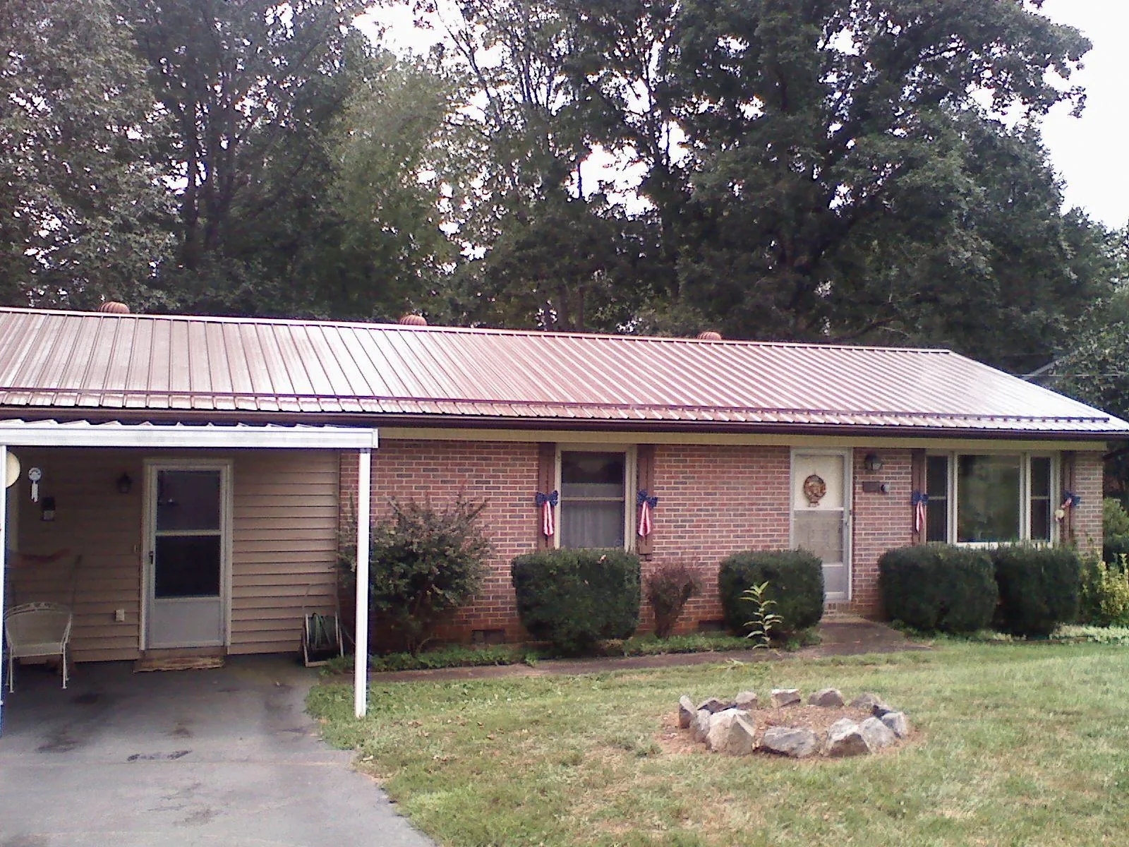 Bronze metal roof and carport on a brick ranch home — Roof Repair work by our crew in Thomas